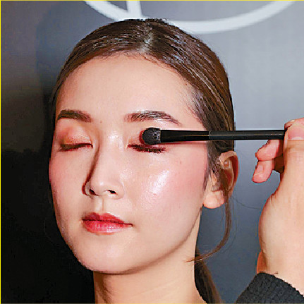 先用眼影組合的霧面淺啡色眼影掃上整個眼窩打底，再混合細緻金色珠光蜜桃粉紅色與閃亮蛋白石色提亮，營造立體感。