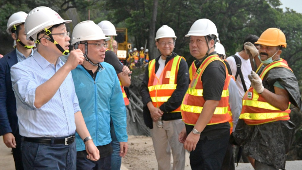 李家超（左一）和運(yùn)流局局長林世雄（左二）為路面修復(fù)工程的工作人員打氣。