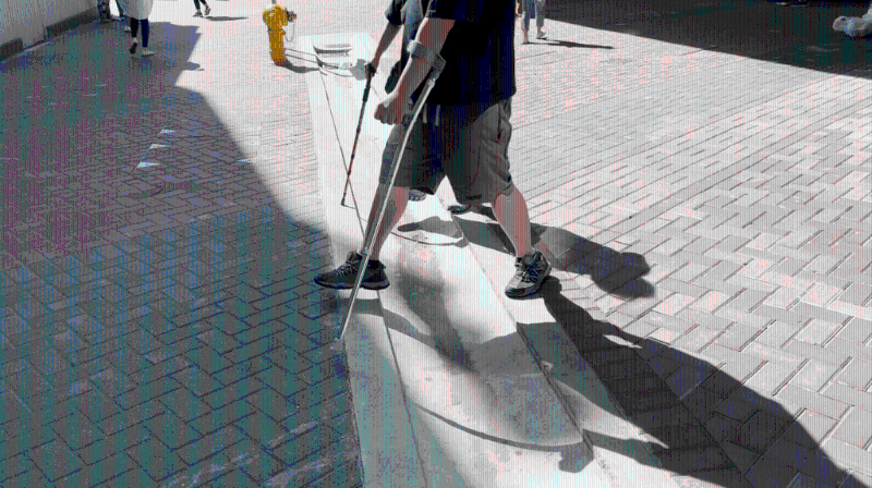 有撐拐杖人士小心翼翼地跨過(guò)坑渠。