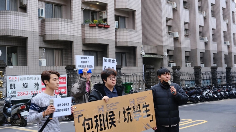 中國文化大學學生在出租套房凱旋苑前高舉標語抗議，呼吁侯友宜正面回應凱旋苑漲租議題，讓房租合理化。