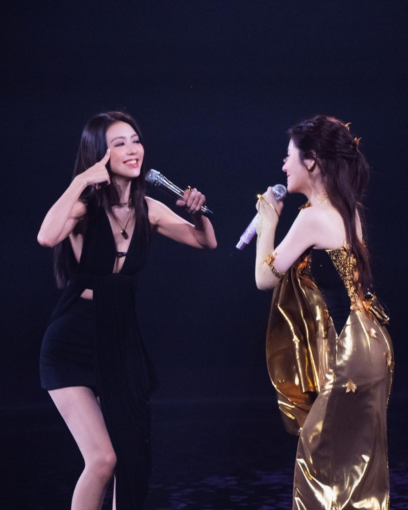 照片中，薛凱琪身穿一件黑色超低胸交叉綁帶背心配黑色短褲，同女星張碧晨手拖手同臺合唱。