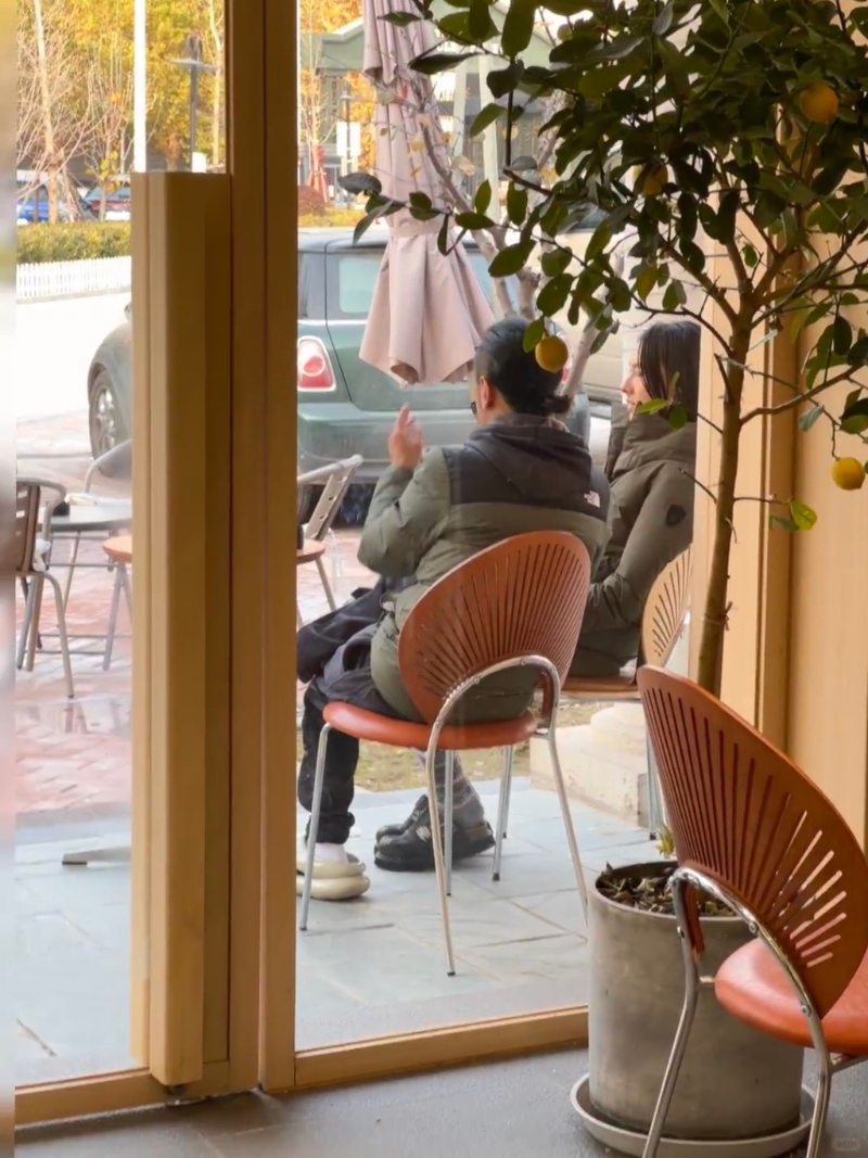 梁洛施與馬浴柯均穿著軍綠色羽絨，二人坐在店外的椅子上閑聊。