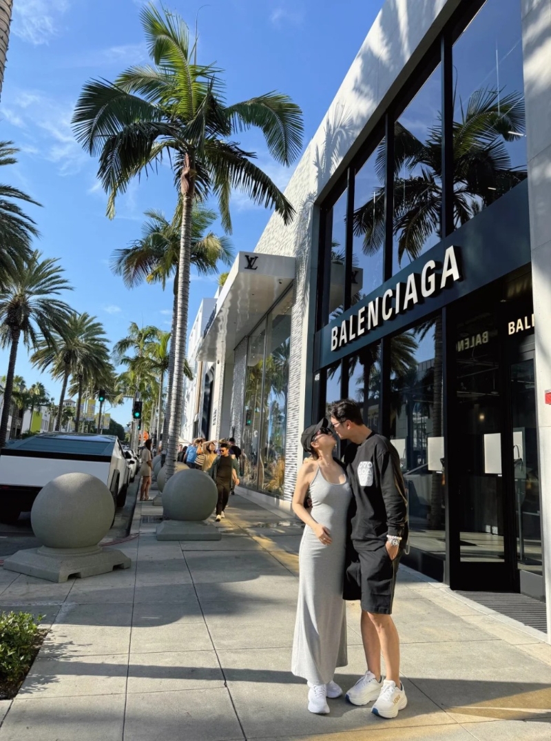 高鈞賢與女友在街頭甜蜜咀嘴，他女友皮膚非常白皙且身材高?。她身穿灰色貼身吊帶連身裙配白波鞋，用了右手遮肚凸凸的肚子，中指更戴上疑似定婚戒指，孕味濃。