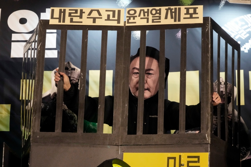 南韓首爾國(guó)會(huì)外要求尹錫悅下臺(tái)的群眾，11日晚間戴上尹錫悅面具置身標(biāo)明「逮捕叛亂首腦尹錫悅」的牢籠，藉此表達(dá)對(duì)于尹錫悅的強(qiáng)烈不滿情緒。（美聯(lián)社）