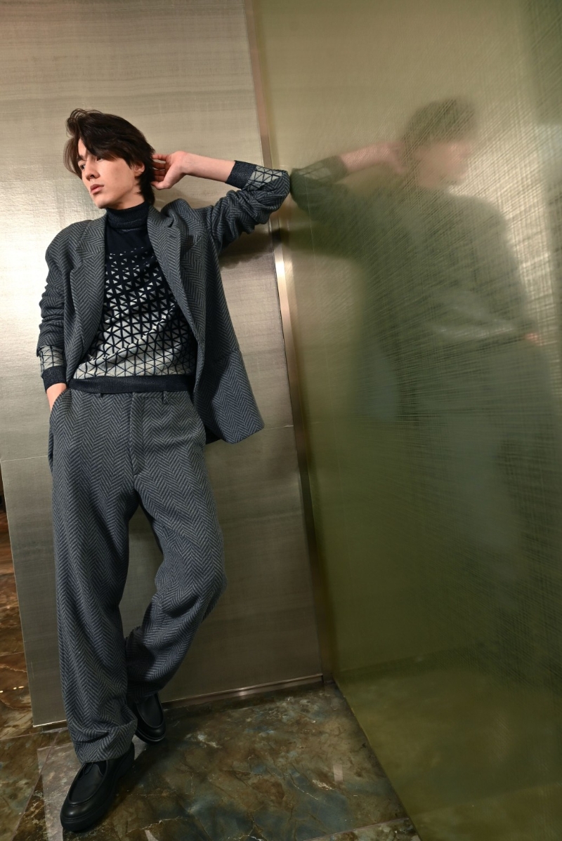 男士西裝的設(shè)計(jì)，絕對(duì)是品牌強(qiáng)項(xiàng)，縱使是冬日的羊毛針織及呢絨配搭，也不見厚重，反覺瀟灑率性。 （灰色寬松西裝外套、深藍(lán)色提花羊毛高領(lǐng)毛衣、灰色長(zhǎng)褲、黑色皮鞋。 ）