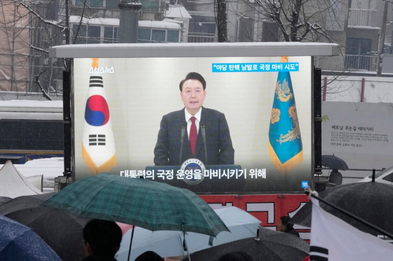 南韓總統(tǒng)尹錫悅因戒嚴(yán)遭國(guó)會(huì)彈劾停職，數(shù)度拒絕檢方傳喚調(diào)查。總統(tǒng)官邸外的挺引群眾5日圍在電視熒幕前收看新聞報(bào)導(dǎo)。（資料照／美聯(lián)社）