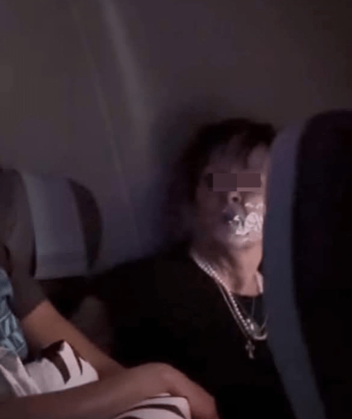 另一張出現(xiàn)在當?shù)孛襟w的照片，婦人被綁在座位上，嘴巴封上透明膠紙，雙目怒瞪著坐在鄰座看守她的空姐。.png