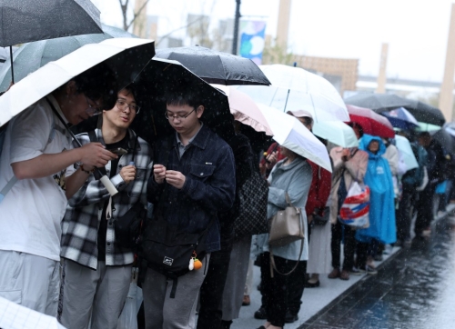 大阪世博開幕首天下大雨，民眾狼狽撐傘排隊(duì)入場(chǎng)。新華社