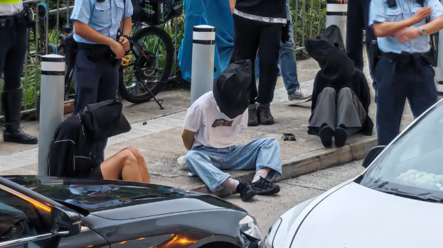 其中兩男一女被捕後戴上頭套坐在地上。