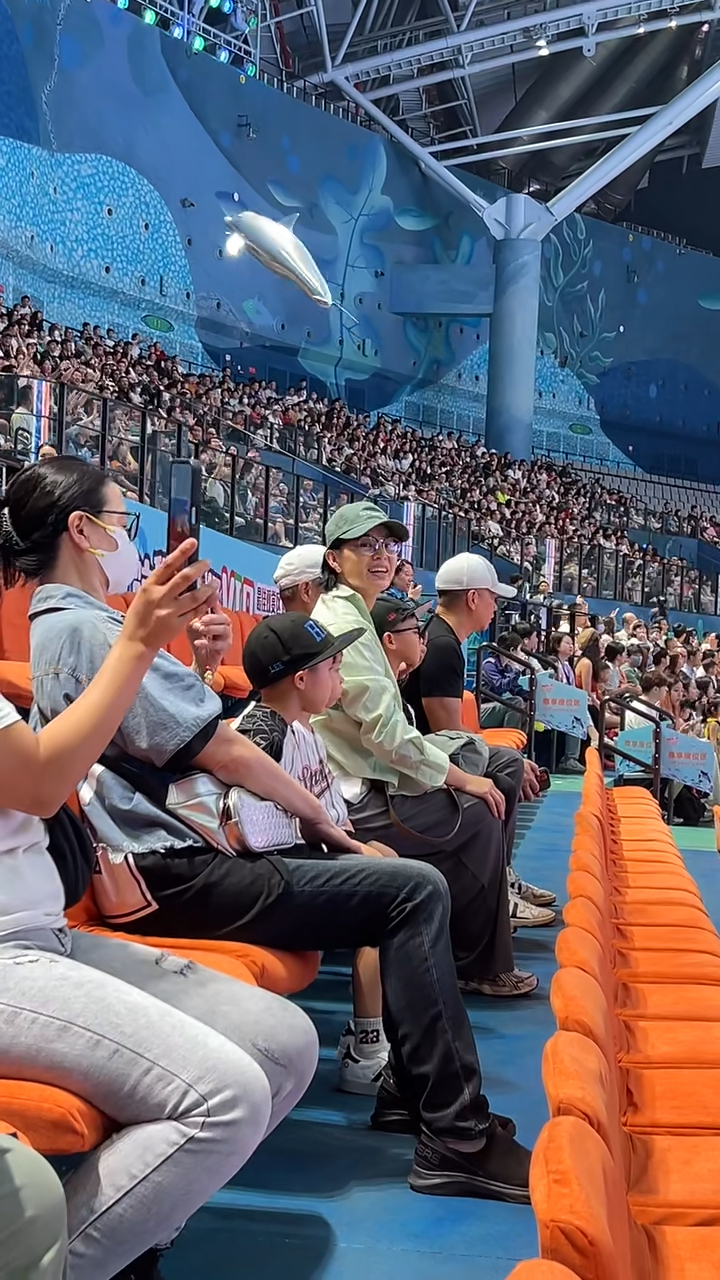胡杏兒頭戴綠色Cap帽及身穿淺綠色襯衫，與家人一起坐在VIP區(qū)域觀看演出，她臉上掛滿笑容，時不時還揮手互動，看起來心情大好。