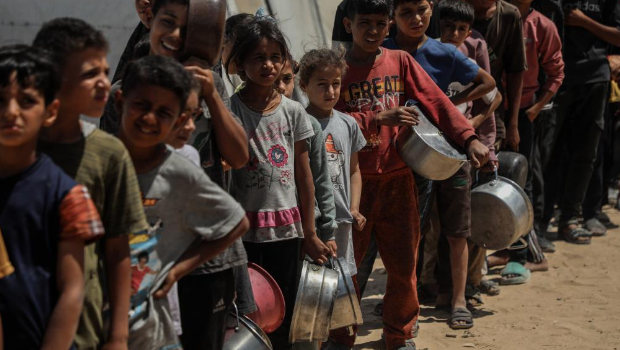 孩子們在加沙城西部的沙提難民營等待領取救助食物。